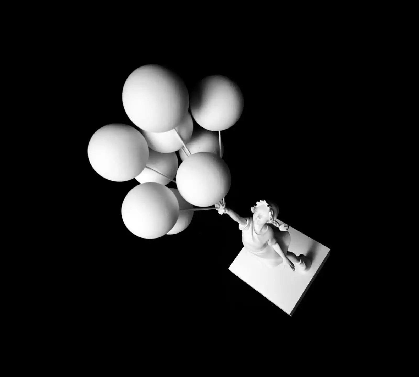 Monochrome sculpture of a girl holding balloons.